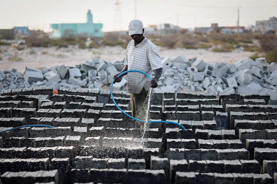 42-летний Моктар Диалло поливает свежеизготовленные кирпичи