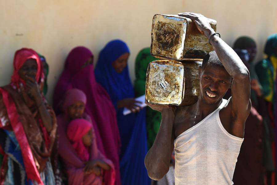 Villagers wait as tins of palm oil are delivered as part of the food distribution from charity Action Aid in Sayla Bari, Somaliland. (Photo by Joe Giddens/PA Images via Getty Images)