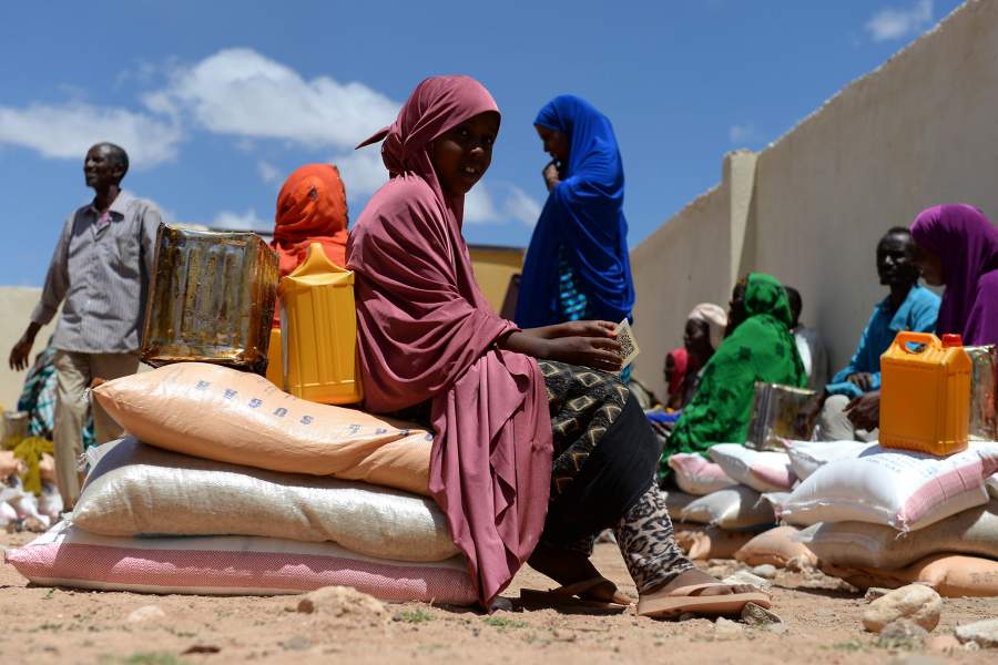 Villagers sit on their bags of rice, sugar, dates and palm oil during the food distribution from charity Action Aid in Sayla Bari, Somaliland. (Photo by Joe Giddens/PA Images via Getty Images)