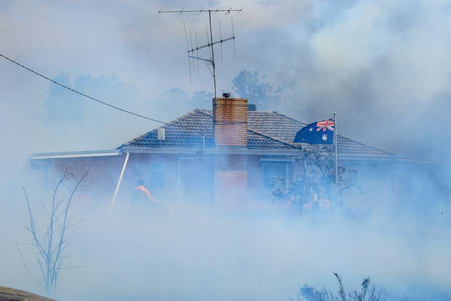 An Australian flag waves as Country Fire Authority (CFA) members douse a home in Longwood in Victoria, Australia January 9, 2026. AAP/Michael Currie/via REUTERS ATTENTION EDITORS - THIS IMAGE WAS PROVIDED BY A THIRD PARTY. NO RESALES. NO ARCHIVES. AUSTRALIA OUT. NEW ZEALAND OUT. NO COMMERCIAL OR EDITORIAL SALES IN NEW ZEALAND. NO COMMERCIAL OR EDITORIAL SALES IN AUSTRALIA.