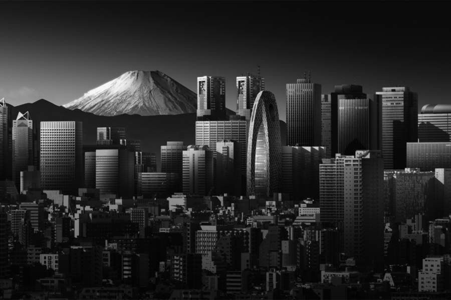 Вертикальный город, Тихий Пик Это вид на городской пейзаж Токио с площади Бункё. Контраст между рукотворными сооружениями и вневременной формой горы создает тонкий диалог, сформированный порядком, масштабом и светом. Выполненная в черно-белом цвете, она избавляет от отвлекающих цветовых акцентов, позволяя сосредоточиться на структуре и тональном балансе. Взаимосвязь между зданиями и далекой вершиной вызывает внутреннее напряжение, определяемое ритмом и пространством.