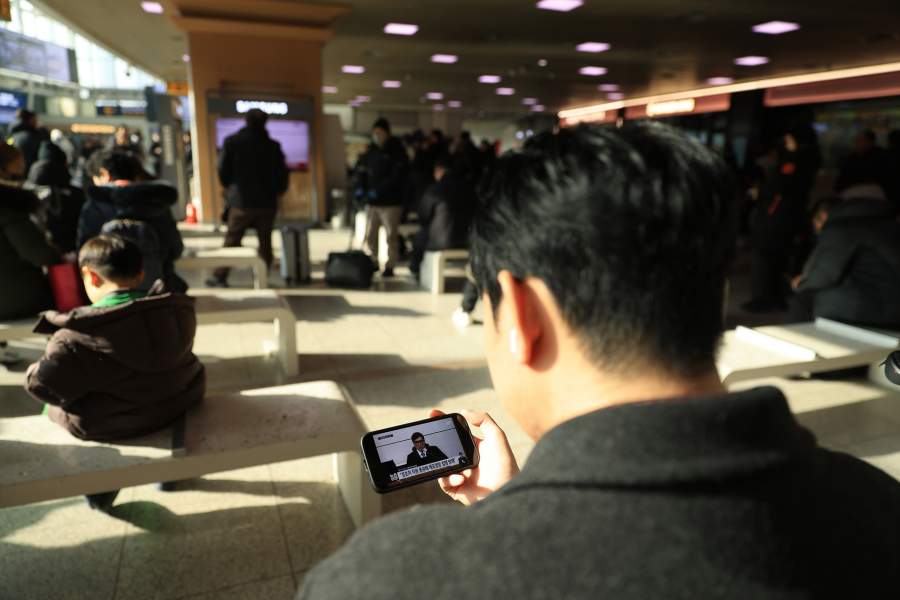 People watch a televised news report on Yoon Suk-yeol's court trial at Seoul Railway Station in Seoul, South Korea, on Jan. 16, 2026. South Korea's former impeached President Yoon Suk-yeol was sentenced to five years in prison on arrest obstruction charges, live footage showed Friday