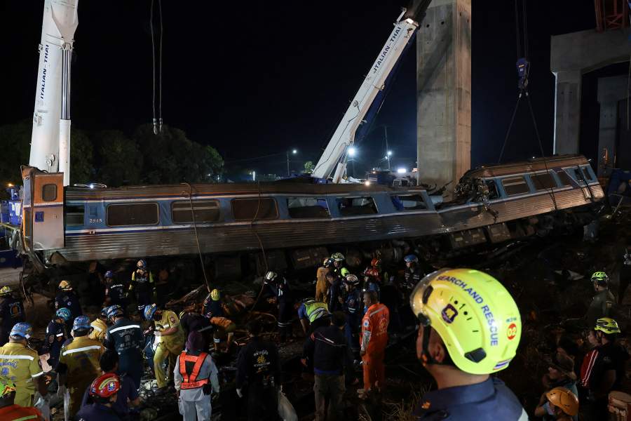 Rescue workers search the site where a train was derailed when a construction crane collapsed and fell onto its carriages, causing several casualties, in Sikhio district, Nakhon Ratchasima province