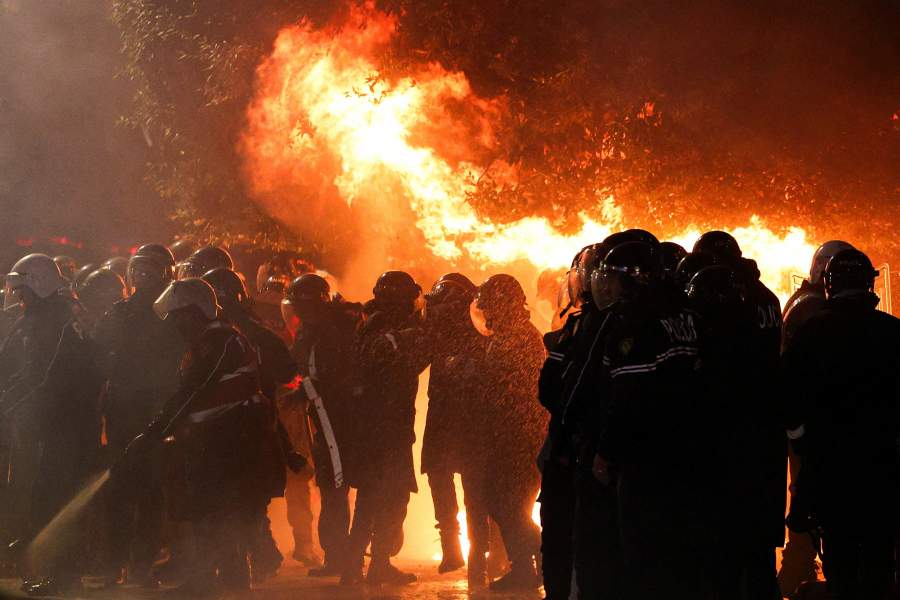Law enforcement officers stand guard as other officers extinguish a fire outside the Prime Minister's office during an anti-government protest triggered by a corruption investigation into Deputy Prime Minister Belinda Balluku, in Tirana, Albania, January 24, 2026