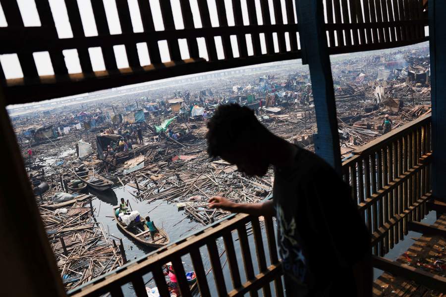 A person walks through the remains of partially demolished stilt houses as authorities continue burning leftover structures in the Makoko riverine community in Lagos, Nigeria, January 25, 2026. Officials are removing structures, including homes and schools, near power lines, in a wider push to recover lagoon side land from the historic fishing community often called the "Venice of Nigeria." REUTERS/Sodiq Adelakun