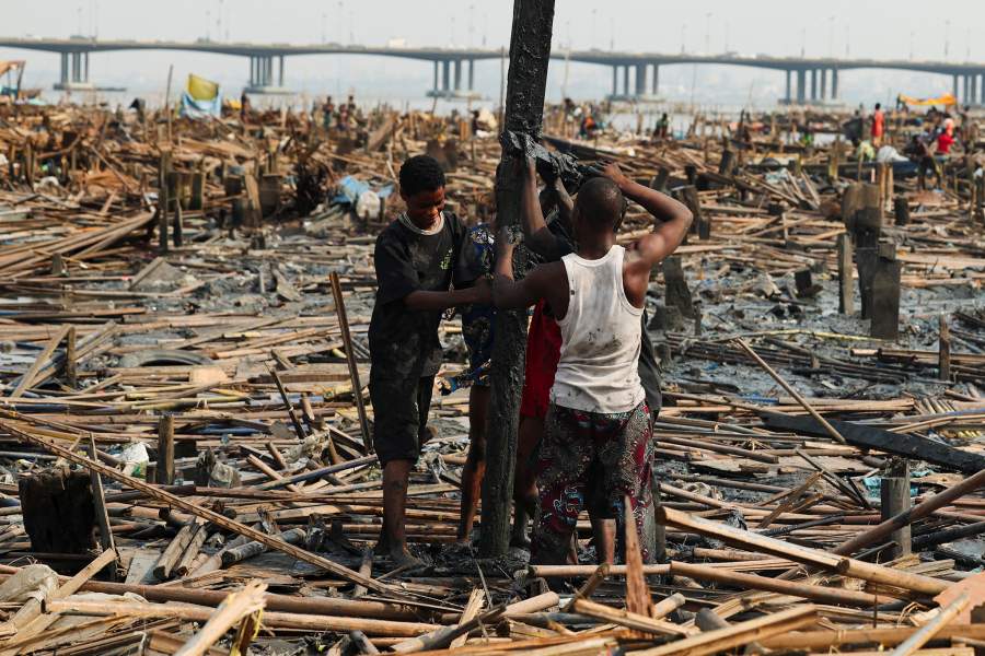 People attempt to romove the remains of demolished stilt houses as authorities burn leftover structures in the Makoko riverine community in Lagos, Nigeria, January 25, 2026. Officials are removing structures, including homes and schools, near power lines, in a wider push to recover lagoon side land from the historic fishing community often called the "Venice of Nigeria." REUTERS/Sodiq Adelakun