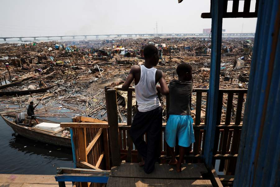 Prosper Atungbe, 7-year-old, looks over the remains of his community with his brother as authorities burn leftover structures in the Makoko riverine settlement in Lagos, Nigeria, January 25, 2026. Officials are removing structures, including homes and schools, near power lines, in a wider push to recover lagoon side land from the historic fishing community often called the "Venice of Nigeria." REUTERS/Sodiq Adelakun
