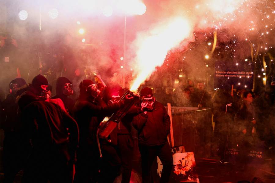 A group of masked protesters gather as one of them fires a flare during an anti-government protest, triggered by a corruption investigation into Deputy Prime Minister Belinda Balluku, in front of the Prime Minister's office in Tirana, Albania