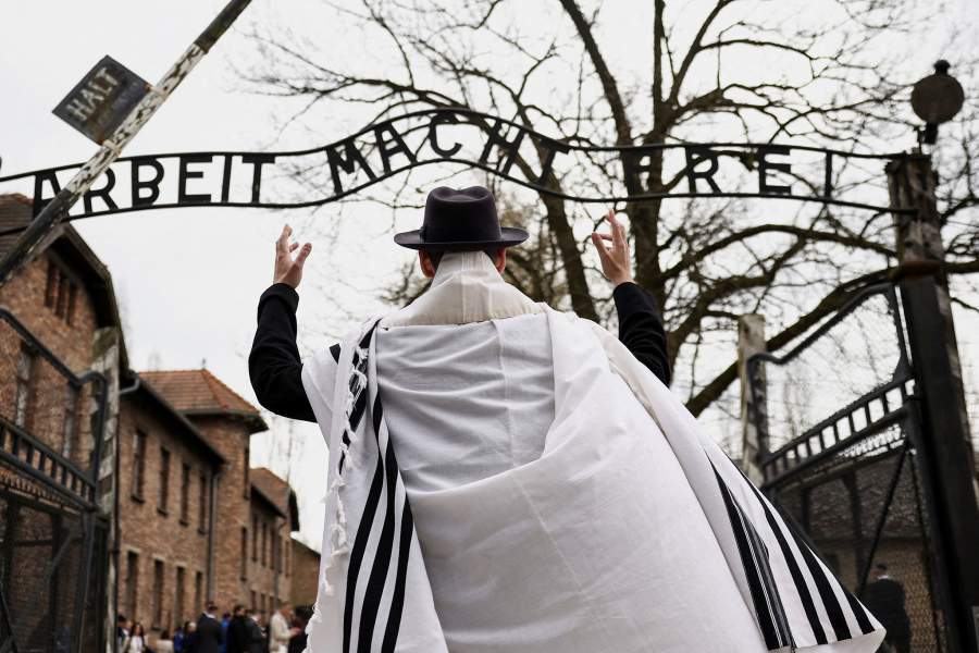 A person gestures in front of the gate with the phrase 'Work sets you free', in German, at the Auschwitz Museum on the day of the annual international "March of the Living" through the grounds of the former Auschwitz death camp, to pay tribute to the millions of Jews murdered by the Nazis during World War Two, in Oswiecim, Poland, April 14, 2026