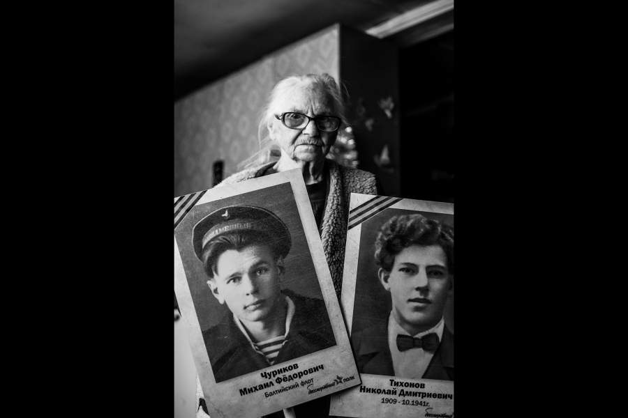 Валентина Николаевна держит в руках штенднры в память о своём муже и отце. Слева изображен Чуриков Михаил Фёдорович — муж, а справа Тихонов Николай Дмитриевич — отец. «Отца убили на войне... Приехала девушка и привезла на него похоронку», — вспоминает Валентина Николаевна.