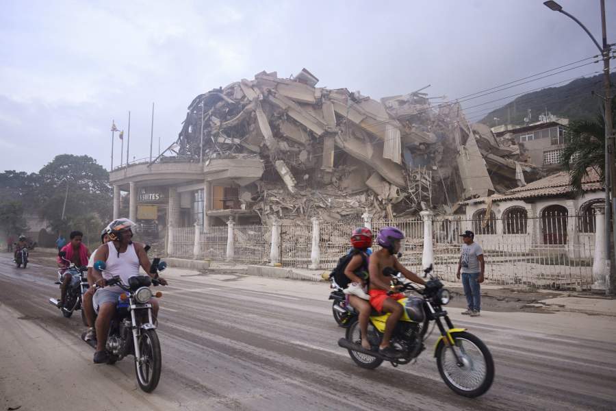 People ride past a collapsed building after an earthquake, in La Guaira, Venezuela, June 24, 2026