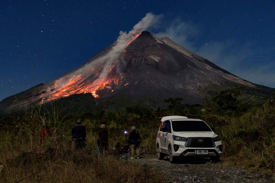 People watch as Mount Merapi volcano spews hot lava and steam as seen from Srumbung, in Magelang, Central Java province, Indonesia, July 3, 2026