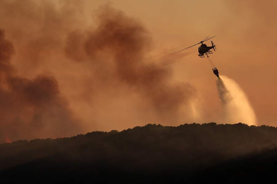 A firefighting helicopter battles a wildfire near Calonge, Spain, July 3, 2026
