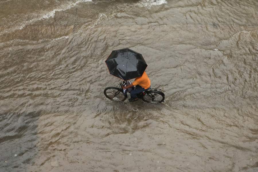 A man cyles through a waterlogged street while holding an umbrella after heavy rains in Mumbai, India, July 4